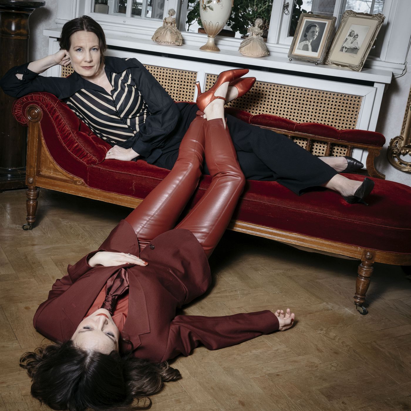 Julia och Yohanna poserar vid en röd schäslong, den ena liggande på golvet
